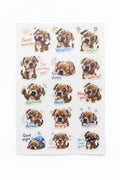 A sheet of cartoon dog stickers with various expressions and colorful text labels, photographed on a light gray textured fabric surface.