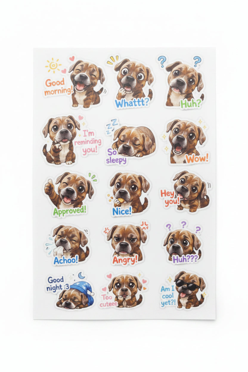 A sheet of cartoon dog stickers with various expressions and colorful text labels, photographed on a light gray textured fabric surface.