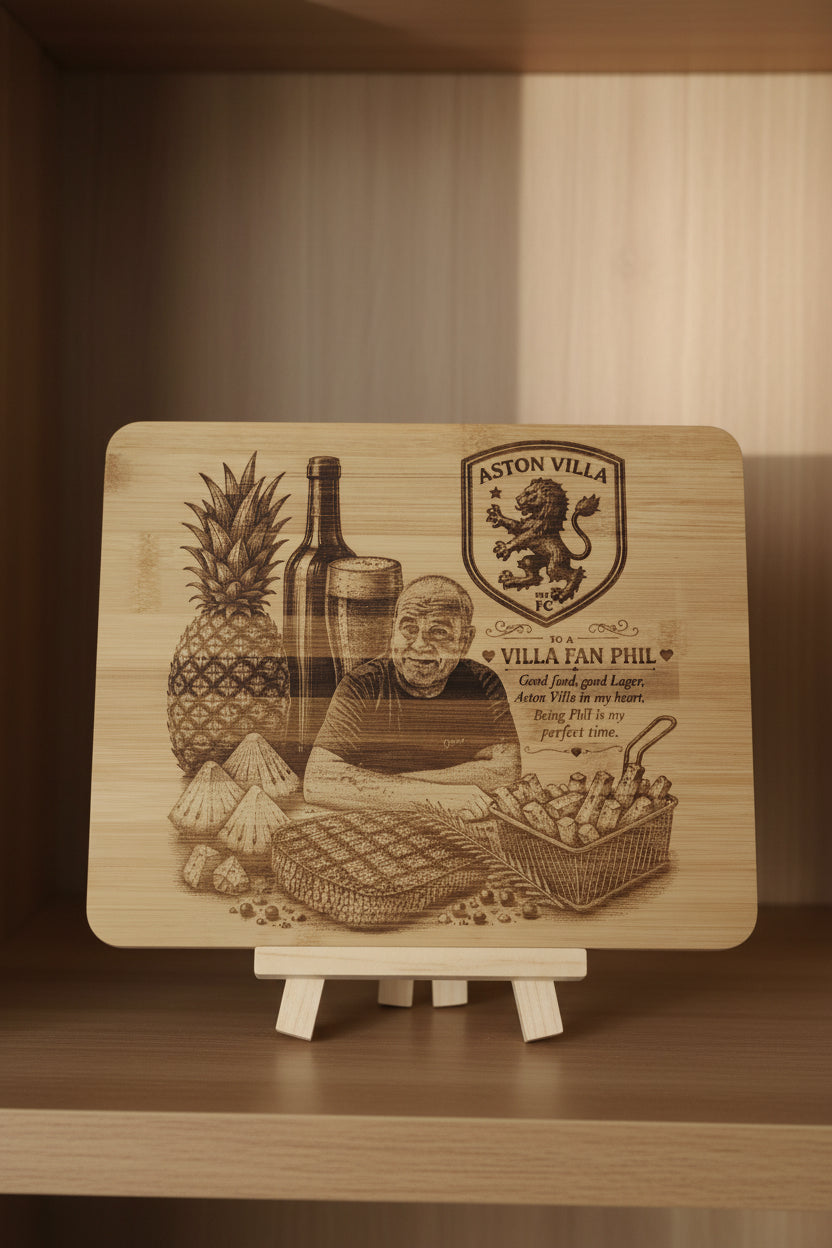 A rectangular wooden board with rounded corners, featuring a laser-engraved design of a pineapple, a bottle, a glass, a lion crest, and a fan Phil graphic, placed on a gray textured fabric surface.